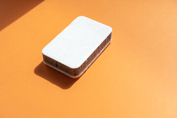 One grey kitchen sponges on the orange background