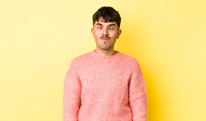 young adult hispanic man looking goofy and funny with a silly cross-eyed expression, joking and...