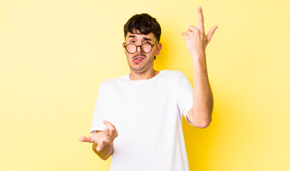 young adult hispanic man shrugging with a dumb, crazy, confused, puzzled expression, feeling...