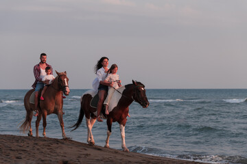 The family spends time with their children while riding horses together on a sandy beach. Selective focus 