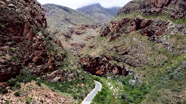 Epic aerial shot travelling through the scenic mountainous landscape which surrounds the Meiringspoort pass, the road below connects the Klein Karoo with the Groot Karoo, South Africa