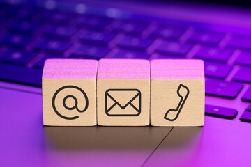Contact us icons on wooden blocks on laptop with colorful lights
