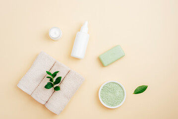 Obraz na płótnie Canvas Cosmetic oil, green bath salt, natural soap, towels and face cream on neutral beige background. Top view, flat lay, copy space