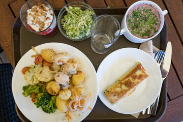 Riga, Latvia, May 21, 2022 A tray filled with a hearty lunch with potatoes, sallad, red beet soup, and dessert.