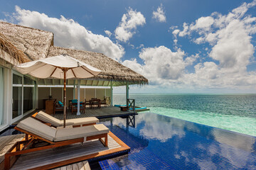Beautiful luxury water villas resort, infinity swimming pool, beach chairs. Tranquil sunny sky,...