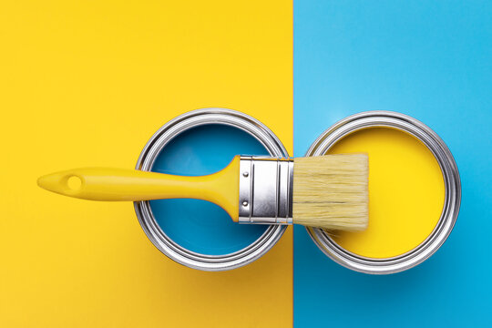 Can of yellow paint with brush on yellow and blue background. Top view, repair concept.