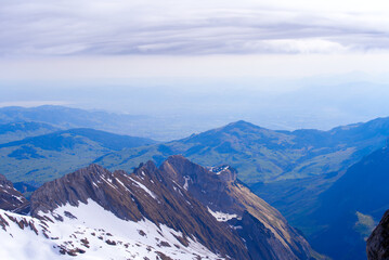 Aerial view with Mountains and midland and lake Bodensee in the background seen from Säntis peak at Alpstein Mountains on a sunny spring day. Photo taken April 19th, 2022, Säntis, Switzerland.