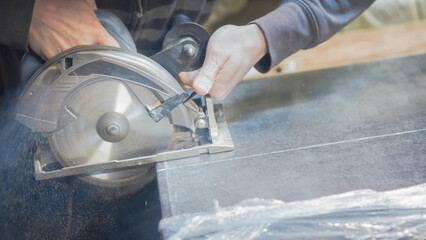  carpenter cuts a wooden panel with a power tool