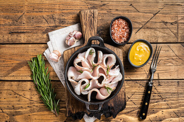 Fresh sliced lard with salt, garlic and pepper in pan with herbs. Wooden background. Top view