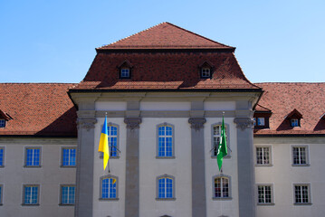 Flags of Canton St. Gallen and the Ukraine at government building blowing in the wind on a sunny spring day. Photo taken April 19th, 2022, St. Gallen, Switzerland.