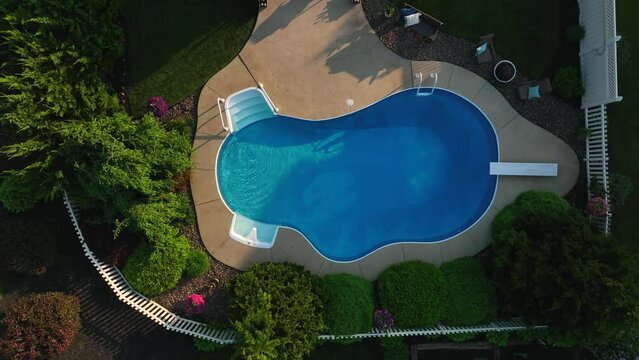 Top down aerial rising shot of pool. Backyard home swimming pool ready for summer swim. Drone view at dusk on spring day.