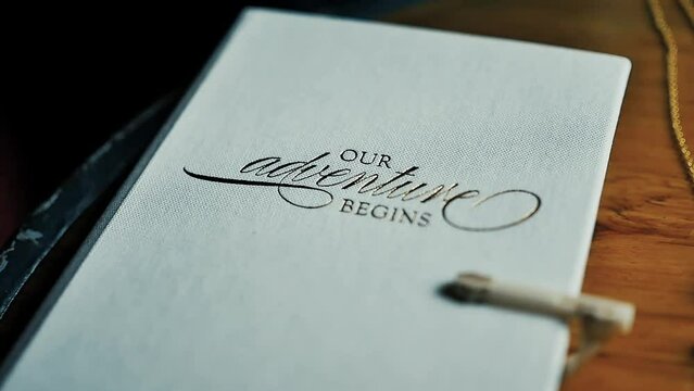 A journal for a wedding that reads "OUR adventure BEGINS"