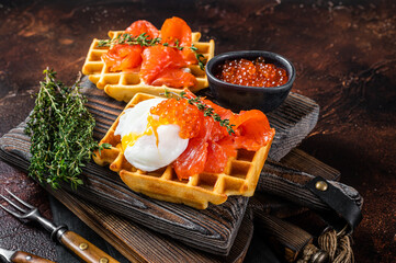 Waffle Sandwich with cream cheese, smoked salmon, egg and red caviar. Dark background. Top view