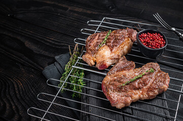 BBQ Grilled Chuck eye Roll beef steaks on grill. Black Wooden background. Top view. Copy space