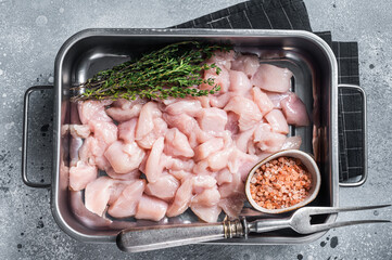 Fototapeta na wymiar Diced raw chicken breast fillets in steel tray. Gray background. Top view