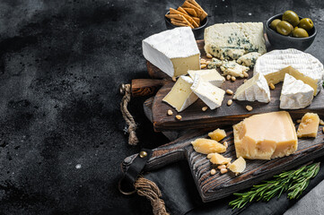 Fototapeta na wymiar Delicious Cheese board. Assortment of cheese, camembert, brie, Gorgonzola, parmesan, olives, nuts and herbs. Black background. Top view. Copy space