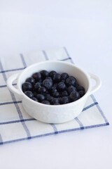 Large garden blueberries in a white plate on a blue checkered napkin. Blue garden berry. Food photography, top view