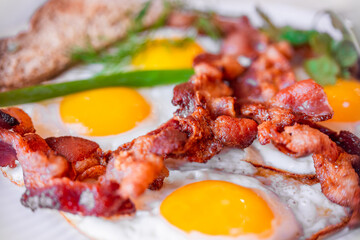 Tasty fried eggs eggs and crispy bacon, close-up, great classic breakfast. Macro photography, shallow depth of field.