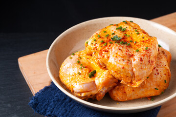 Food concept homemade spicy chicken thighs marinade in ceramic bowl on wooden board with black background and copy space