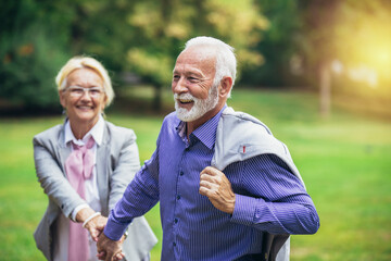 Senior active caucasian couple holding hands looks happy in the park in the afternoon