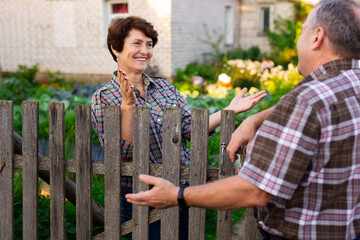 neighbors man and woman chatting near the fence in the village