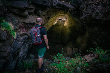 explorer enters a cave in the forest