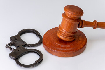 Wooden judge's gavel and police handcuffs on a dark background. Concept: claim and compensation for...