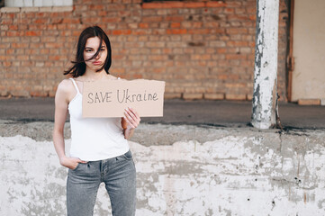 Ukrainian calls to stop war in Ukraine. holds sign Save Ukraine, looks with tired, devastated look