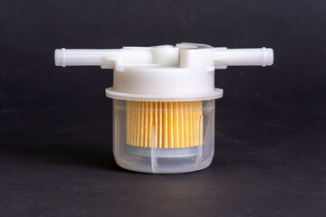Plastic fuel filter for diesel and gasoline engines on a dark background.