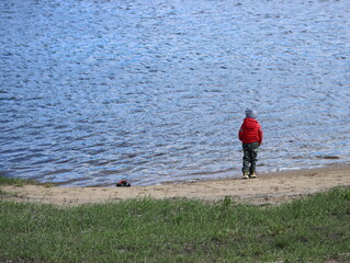 Boy in a red jacket on the background of the river