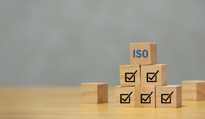 ISO standards quality control certification concept. Quality warranty and assurance. Hand puts wooden cubes with check mark and ISO icons on white background and copy space. Modern ISO banner.