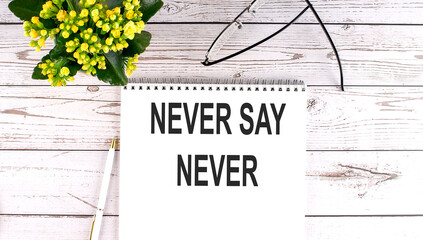 NEVER SAY NEVER text concept write on notebook on wooden background