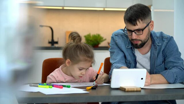 Father and little girl watch video tutorial on tablet and learn to draw on internet at home. Drawing training. Online education