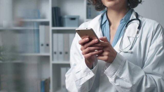 Female doctor with mobile phone in lab coat is talking on phone. Doctor works and searches for information on mobile phone in office. Concept of treatment, technology. Picture to add text message
