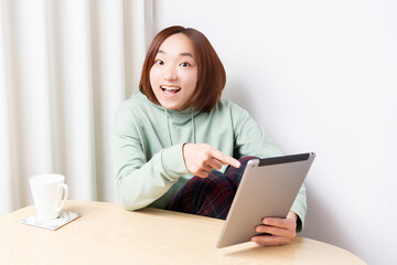 Fototapeta premium 部屋でタブレット端末を使う女性