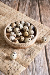 Fresh quail eggs in a basket on a horn and wooden background