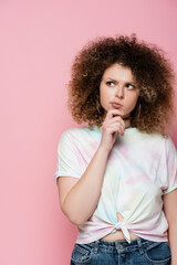 Thoughtful young woman looking away isolated on pink.