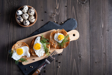Fried quail eggs in a bun on a wooden cutting board.