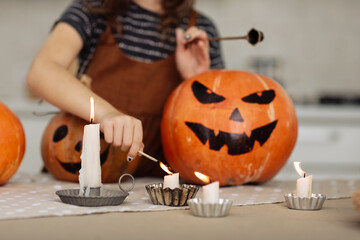 child girl lights a candle for Halloween. little girl in witch costume with carving pumpkin with a face made by child. Happy family preparing for Halloween. selective focus