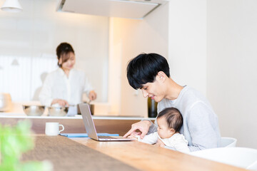 Obraz na płótnie Canvas 赤ちゃんと一緒にパソコンを使うパパ