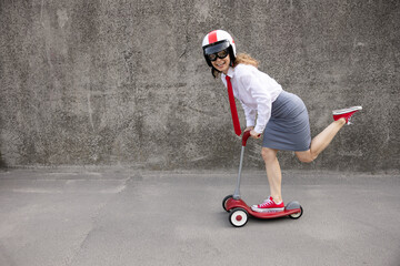 Funny businesswoman riding scooter outdoor