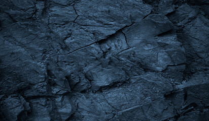 Dark blue rock texture. Toned rough mountain surface with cracks. Close-up. Stone background with...