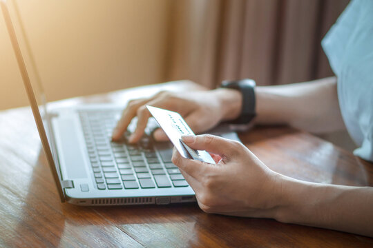 Woman relaxing at home and browsing internet with Laptop, hands holding credit card, using banking service, online shopping.