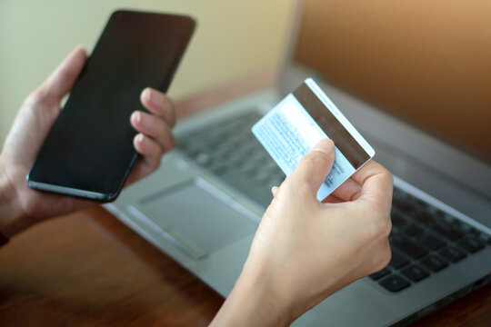 Woman relaxing at home and browsing internet with Laptop, hands holding mobile smart phone and credit card, using banking service, online shopping.