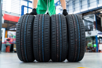 Obraz na płótnie Canvas Auto Mechanic with 4 new tires in Car repair center.