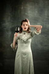 Emotional young beautiful girl, actress in image of medieval person posing isolated on dark background. Comparison of eras concept, flemish style. Art, beauty