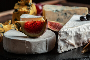 Various kind of cheese, traditional pieces of french, italy and spanish manchego cheese with grapes and figs served on wooden table