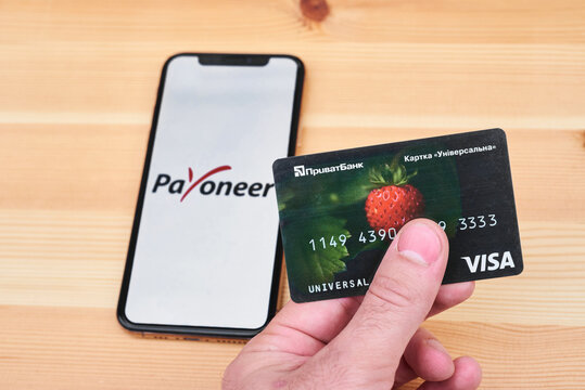 Ukraine, Kyiv, May 3, 2022 - PrivatBank card on the background of the flag of Ukraine and the payoneer logo. payoneer app icon. payoneer launches in Ukraine.