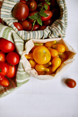 Market delivary of Different kinds of tomatoes in eco textile bag, Zero waste, Eco background, Assortment of tomatoes,  local farmers market, Fresh vegetables, harvest .Top view, copy space.