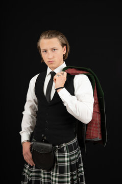 blonder, junger Mann tr&auml;gt einen Kilt und Trachtenjacke &uuml;ber der Schulter